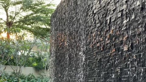 Streams of water fall along a vertical fountain wall built from stone blocks 库存影片 333632718