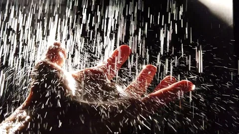 Streams of water fall on the hand, in drops of water reflected sunlight. Vidéo 108132242