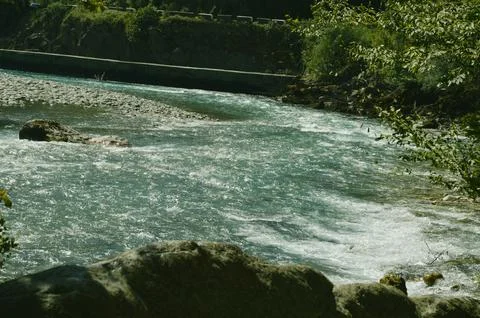Streams of water from a river flowing over rocks between mountains with gre.. Stock Photos