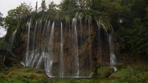 Streams of waterfall fall from rock. Green rocky shore of Plitvice Lake, Croatia Video stock 126242115