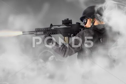Street assault, riot police firing his submachine gun, smoke Stock Photos