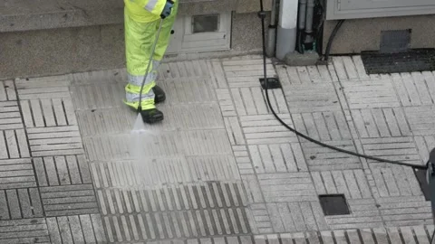 Street cleaner is using a pressure washer to clean a city sidewalk Vídeos de archivo 302913636