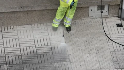 Street cleaner is using a pressure washer to clean a city sidewalk Video stock 302913650