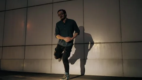 Street dancer performing slow motion twist moves against modern city backdrop Stock Footage 303646114