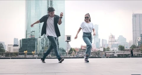 Street dancing fun. Young man and his friend practice freestyle dance move in Stock Footage 106374176