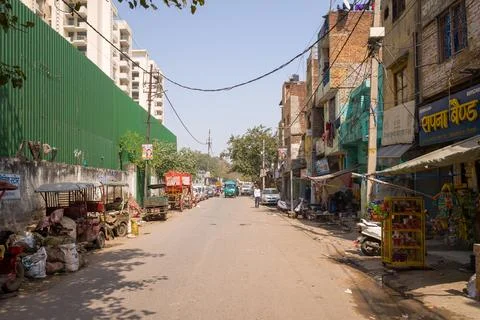 Street with e-rickshaws, small shops, and residential buildings in Karol Bagh Stock Photos