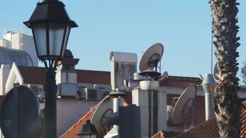 STREET LAMP WITH ROOFTOP BACKGROUND WITH PARABOLIC ATENNAS ON A SUNNY MORNING Video stock 213970370