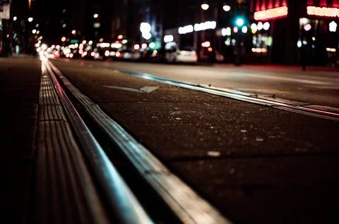 Street level selective focus on trolley rail lines at night in San Diego. Stock Photos