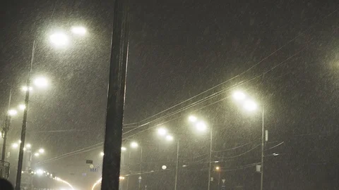 Street light glowing in dark winter night. City lantern in falling snow at Stock Footage 122728186