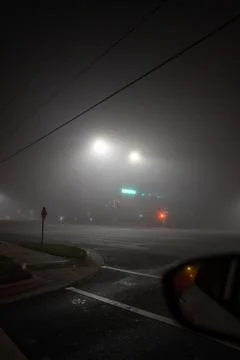 Street lights illuminate an empty intersection on a foggy night Stock Photos
