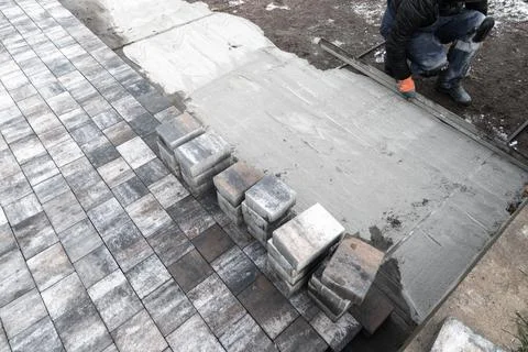 Street paving is in progress. Worker with gray paving slabs Stock Photos