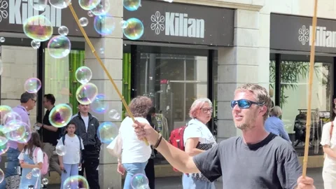 Street Performer Creating Giant Soap Bubbles in a Pedestrian Zone Stock Footage 341437668