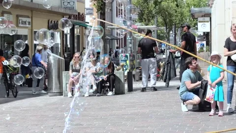 Street Performer Creating Giant Soap Bubbles from a Bubble Solution Bucket Stock Footage 341438071