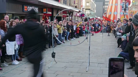 Street performer jumping through hoops with crowds watching Stock Footage 169100012