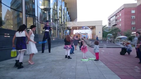 Street performer making large soap bubbles for children to chase Stock Footage 50080307