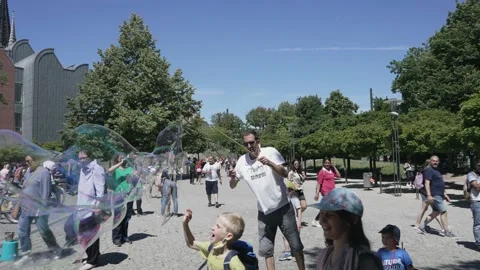 Street performer men making giant soap bubbles on an early summer afternoon ente Stock Footage 233733676