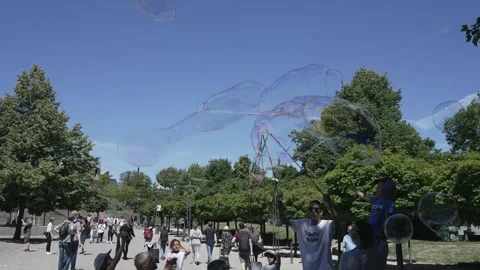 Street performer men making giant soap bubbles on an early summer afternoon ente Stock Footage 241043306