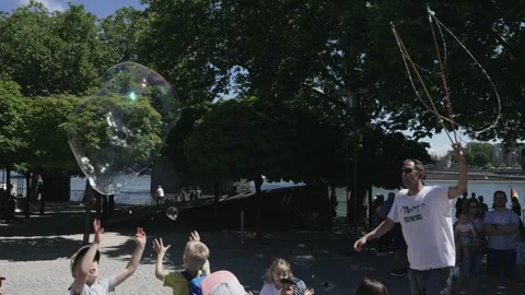 Street performer men making giant soap bubbles on an early summer afternoon ente Stock Footage 246697576
