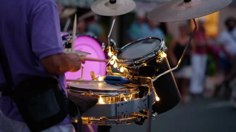 Street performer playing a drum set decorated with glowing lights during an Stock Footage 339809551