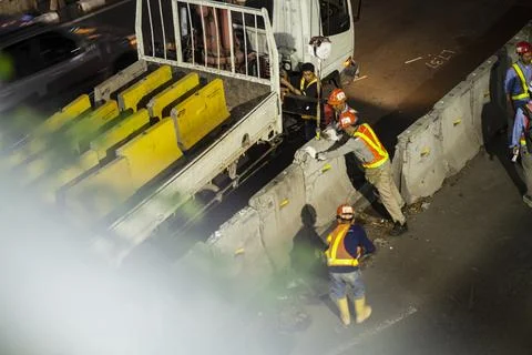 Street project workers complete with heavy equipment work at night Stock Photos
