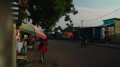 Street with shops both sides and passing car, Ouesso Vidéo 338167755