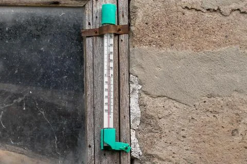Street thermometer on the window of a dilapidated house.Thermometer showing.. Stock Photos