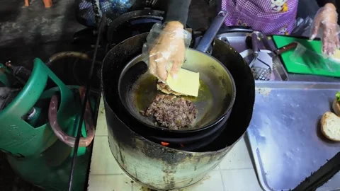 Street Vendor Adding Cheese to Burger Patty While Frying at Thai Night Market Video stock 330571321