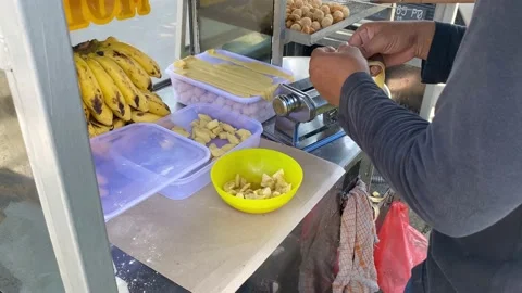 A street vendor is processing bananas to be cooked into fritters Stock Footage 234573425
