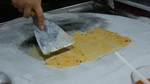 A street vendor skillfully prepares fried ice cream on an icy pan, spreading and Video stock 309933879