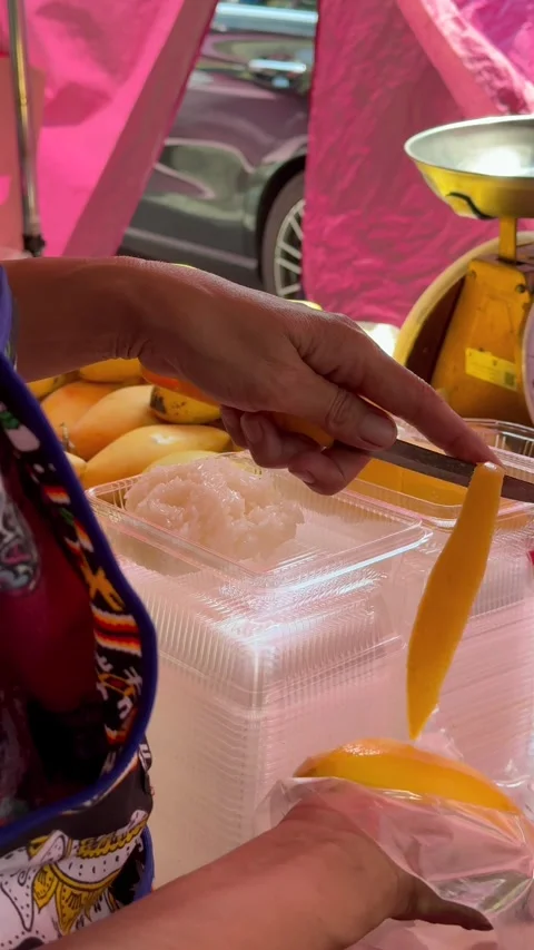 Street vendor slicing mango for mango sticky rice at local market in Thailand Video stock 336596694