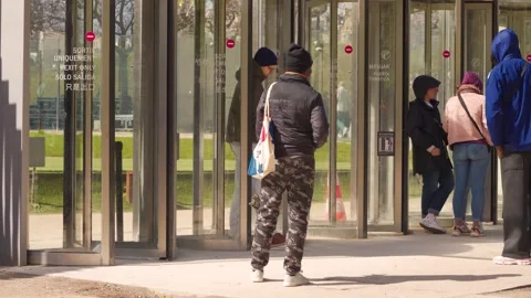 Street Vendor Standing At Eiffel Tower Exit Door With Tourists Passing, Medium Stock Footage 339686789