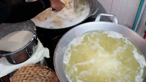 Street vendor using tongs to drop battered bananas into a deep frying pan Stock Footage 337421057