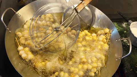 Street Vendor Using Wire Skimmer to Fry Skewered Snack Balls in Bubbling Oil Video stock 330157209