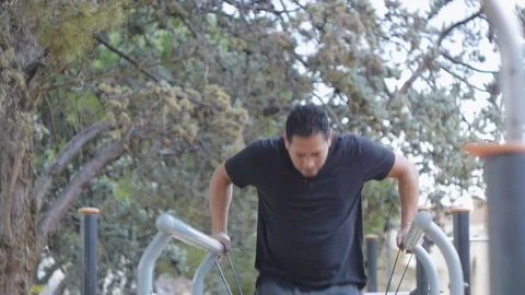 Street workout training. Hispanic man doing parallel bar dips with resistance Stock-Footage 85982932