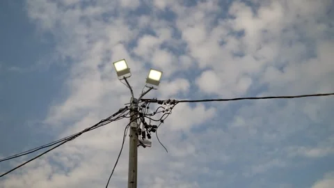 Streetlight pole with electrical wires against cloudy sky Stock Footage 296573539