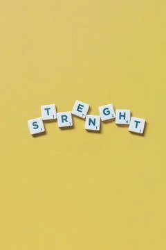 Strength formed of scrabble elements on yellow background. 스톡 사진