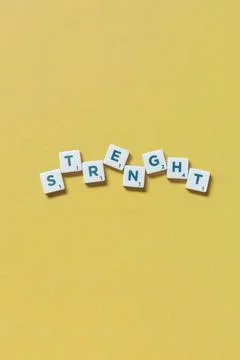 Strength formed of scrabble elements on yellow background. Word strength f... 스톡 사진