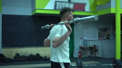 Strength training in the gym. Guy doing squats with an empty barbell. Stock Footage 131028097