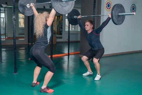 Strength training. Young guy and girl doing sit-ups with weight Stock Photos