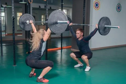Strength training. Young guy and girl doing sit-ups with weight Stock Photos