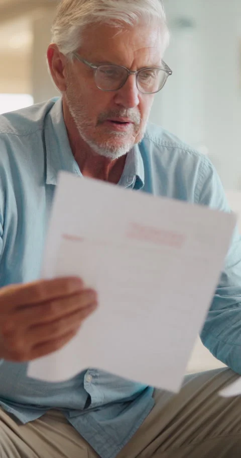 Stress, paperwork and old man in home with worry, confused or reading letter of Stock Footage 335908188