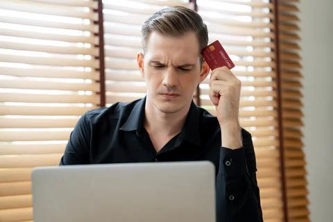 Stress young man sit at at table, pay credit card debt. Unveiling Foto stock