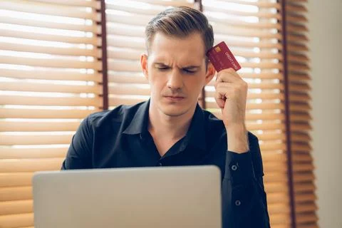 Stress young man sit at at table, pay credit card debt. Unveiling 스톡 사진