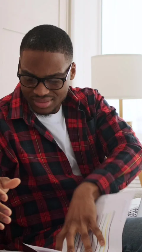 Stressed African American man sorting through documents while working on a Stock Footage 328126533