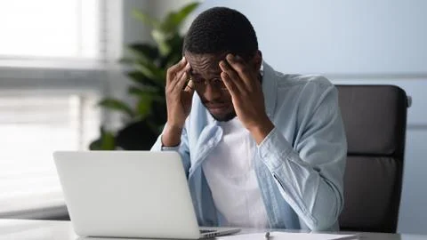 Stressed African worker touching temples feels unhealthy suffers from headache 스톡 사진