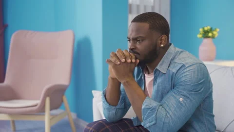 Stressed african young man sitting at home. Unhappy expression. Video stock 228802489