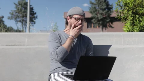 Stressed and bored Man Is Working at His Laptop outdoor Stock Footage 131683930