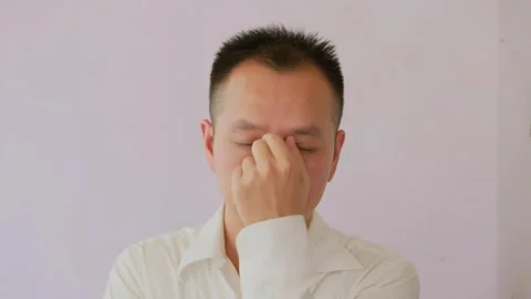 Stressed and exhausted Asian man massages temples 库存影片 342470397