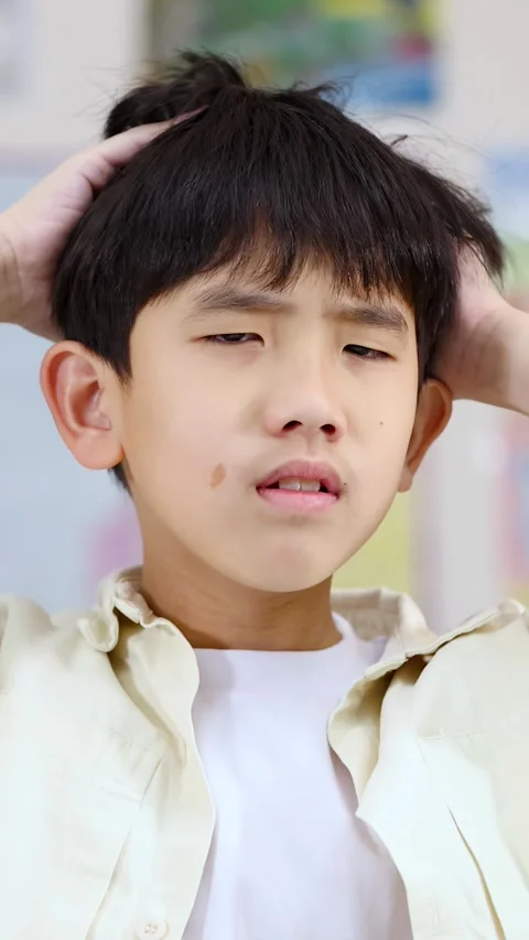 Stressed Asian Boy Holding Head with Confused Expression in Classroom Stock Footage 326386417