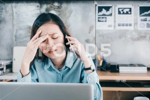 Stressed Asian creative designer woman cover her face with hand and feel upse Stock Photos